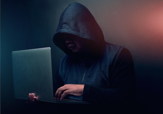Hacker online i człowiek z laptopem w studiu do cyberataku ransomware i oszustwa w bazie danych przestępstwo cyberbezpieczeństwa i osoba z technologią kodowania ryzyka sieciowego lub szkodliwego oprogramowania na czarnym tle
