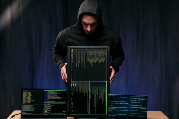 Haker trzymający monitor ze średnim strzałem
