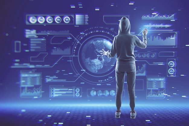 Haker w bluzie z kapturem za pomocą abstrakcyjnego świecącego cyfrowego interfejsu biznesowego z kulą ziemską i różnymi innymi ikonami na rozmytej niebieskiej tapecie Tech hacking koncepcja przyszłości i gospodarki
