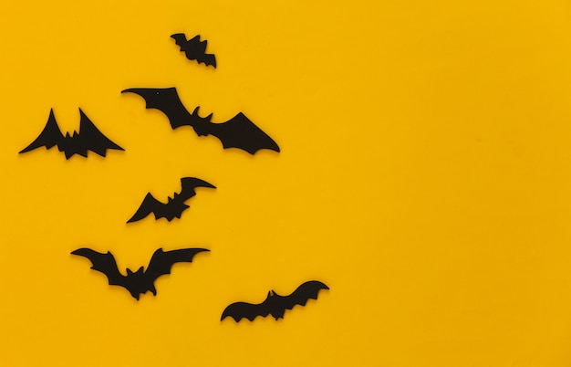 Halloween, dekoracje i straszna koncepcja. Czarne nietoperze latają nad żółtym