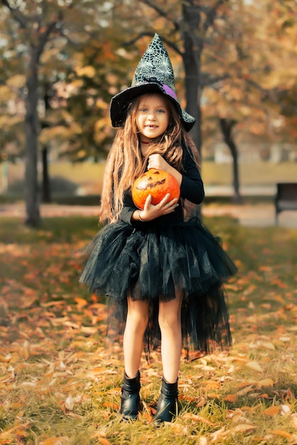 Halloween dziewczyna śmieje się i trzyma w rękach dynię