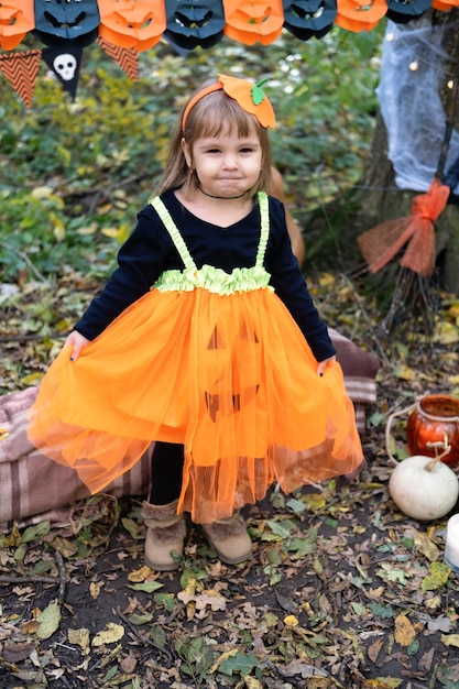 Halloween. śliczna mała dziewczynka w stroju dyni bawi się, świętuje Halloween na świeżym powietrzu