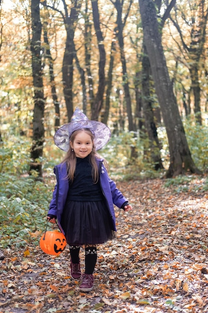 Halloween. śliczna mała dziewczynka w stroju wiedźmy z latarnią Jack o zabawę na świeżym powietrzu