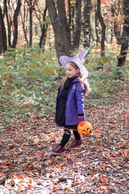 Halloween. śliczna mała dziewczynka w stroju wiedźmy z latarnią Jack o zabawę na świeżym powietrzu