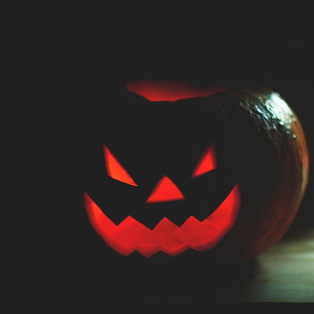 Halloweenowa bania z przerażającą twarzą na czarnym tle