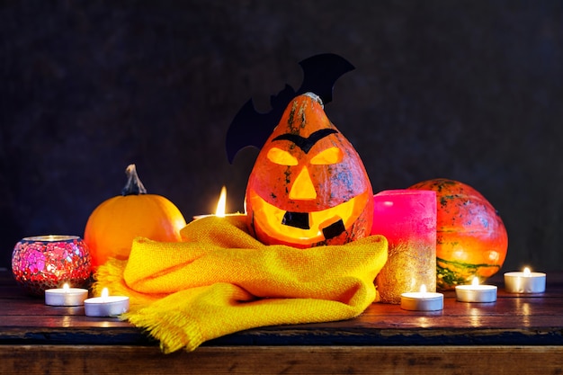 Halloweenowa dynia z płonącymi świeczkami na ciemnym tle. Halloweenowy uśmiech dyni i przerażające oczy. Dekoracje na Halloween