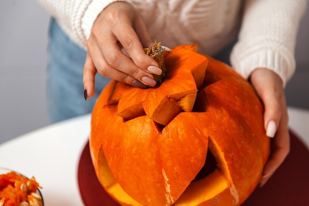 Halloweenowa dynia ze zdjęciami zbliżenia rąk kobiet