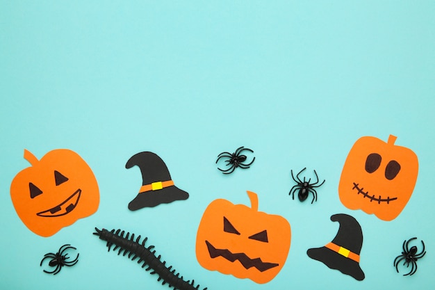 Halloweenowa kompozycja z dynią i pająkami na niebieskim tle.