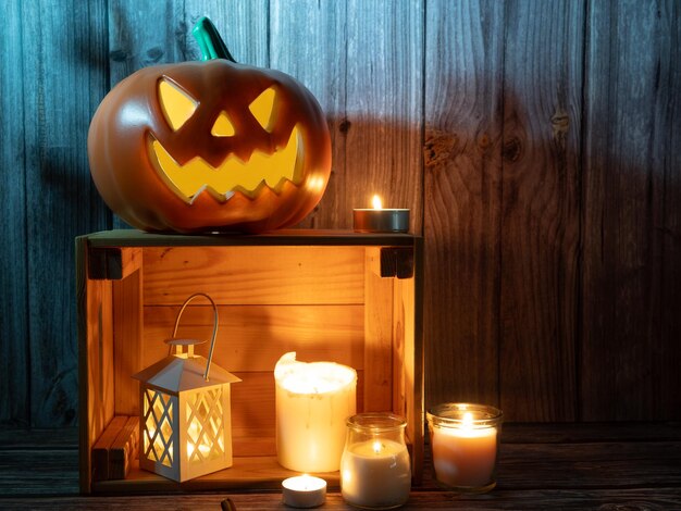 Halloweenowa latarnia z głową dyni ze świecami i dynią na drewnianym tle