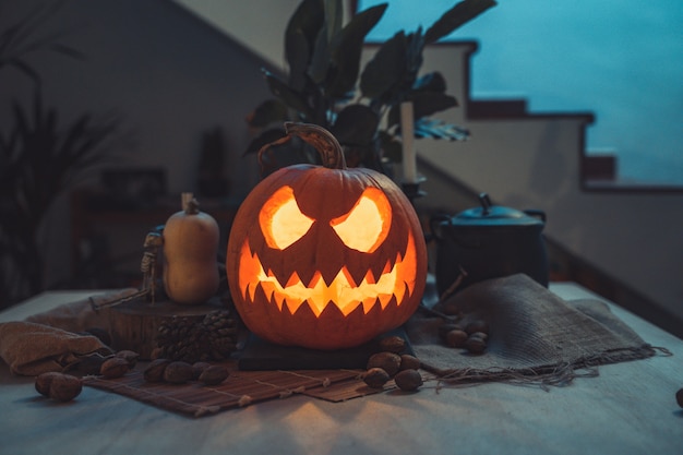 Halloweenowa upiorna twarz dyni w stole z dekoracją Szkieletowe świece orzechy