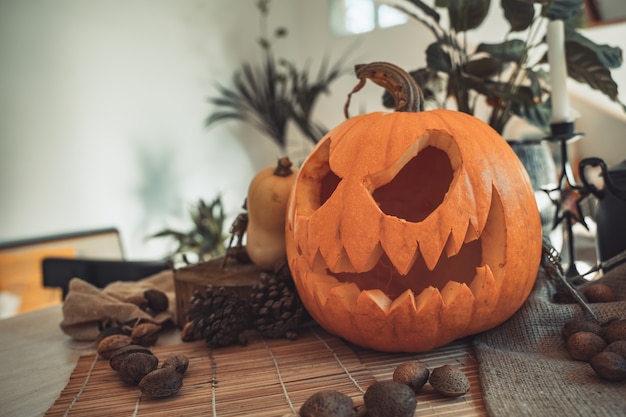 Halloweenowa upiorna twarz dyni w stole z dekoracją Szkieletowe świece orzechy