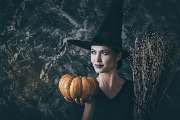 Zdjęcie halloweenowa wiedźma trzymająca dynię i miotłę