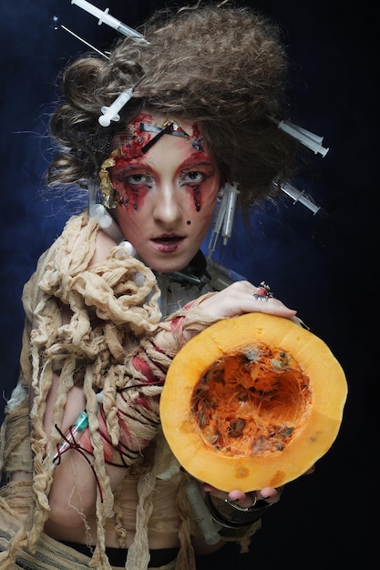 Zdjęcie halloweenowa wiedźma z dyniową młodą kobietą z jasnym makijażem i kreatywną fryzurą