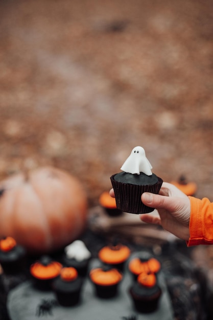 Halloweenowe babeczki i świąteczny wystrój na liściach klonu wśród drzew w sezonie jesiennym na świeżym powietrzu