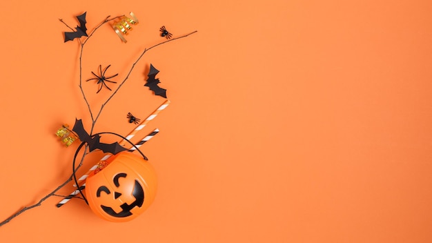 Halloweenowe dekoracje papierowe nietoperze latające na gałęzi drzewa i wiadrze z dyni na pomarańczowym tle