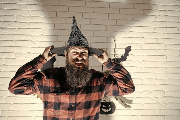 Zdjęcie halloweenowy hipster z brodą na złej twarzy i kapeluszu wiedźmy