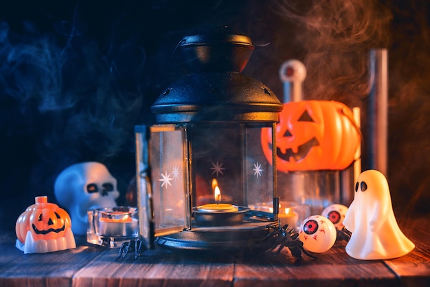 Halloweenowy projekt koncepcji świątecznych upiornych dekoracji świec dyniowych z niebieskim odcieniem dymu wokół ciemnego drewnianego stołu z bliska strzał