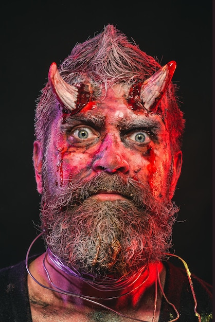 Zdjęcie halloweenowy szatan z brodą, czerwoną krwią, ranami na twarzy