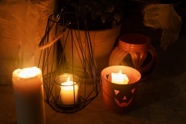 Halloweenowy wystrój werandy i wejścia Upiorny Jack o latarnia pająki dynia i świecące świeczki w wiaderku w ciemności Straszne dekoracje halloweenowe na zewnątrz domu Cukierek albo psikus