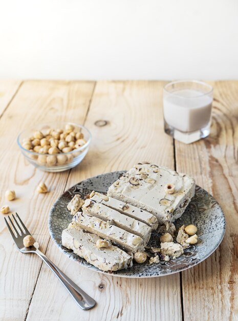 Halwa z orzechami laskowymi na szarym talerzu i drewnianym tle