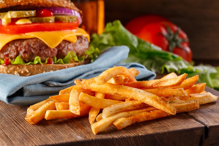Zdjęcie hamburger i frytki zamykamy up na drewnianym tle.