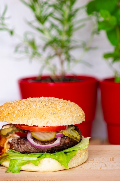 Hamburger Na Desce Do Krojenia W Tle Roślin W Czerwonych Doniczkach