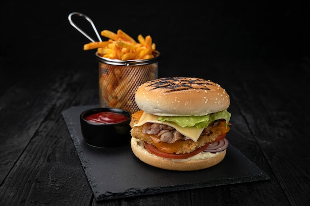 Hamburger z sosem i frytkami na ciemnym drewnianym stole