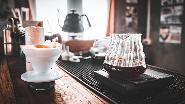 Hand Drip Coffee Barista nalewa gorącą wodę na paloną kawę z filtrem, a mężczyzna nalewa gorącą kawę z dzbanka do białej filiżanki kawy na stole ranovintage