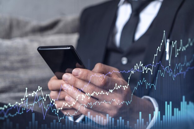 Handlowiec trzymający w rękach inteligentny telefon i badający giełdę, aby kontynuować właściwe rozwiązania inwestycyjne Handel internetowy i koncepcja zarządzania majątkiem Hologram Wykres Forex nad strzałem z bliska