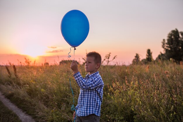 Zdjęcie happy boy spełnia swoje życzenia i marzenia na świeżym powietrzu z balonem piękna letnia karta wolności