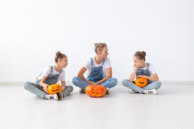 Happy halloween i święta koncepcja - matka i jej córki z dyniami. Szczęśliwa rodzina przygotowuje się do Halloween.