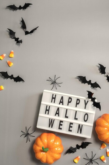 Happy halloween lightbox znak tablica z nietoperzami dyni i cukierkami na szarym tle