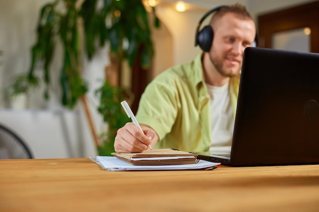 Happy Man w słuchawkach bezprzewodowych ogląda szkolenie webinarowe