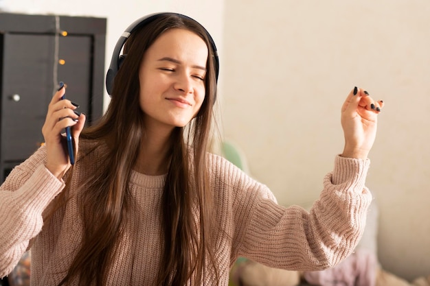 Happy teen girl dancing w słuchawkach w domu uśmiechając się