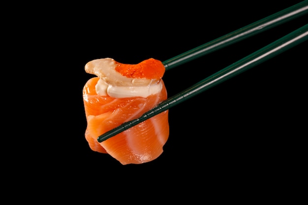 Hashi Trzymać Sushi I Rolki Odizolowane Na Czarnym Tle