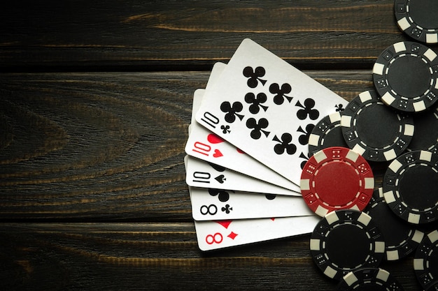 Hazard grając w pokera z wygrywającą kombinacją pełnego domu lub pełnej łodzi Karty z żetonami na czarnym stoliku vintage w klubie pokerowym
