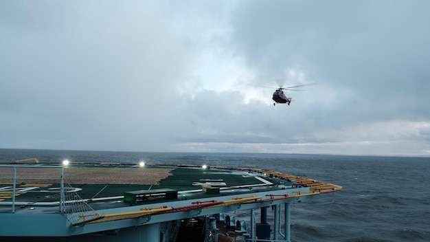 Helikopter ląduje na pokładzie z zawisem. Lot szkoleniowy z lądowaniem szkoleniowym na lądowisku śmigłowca poruszającego się statku.