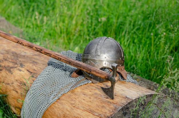 Hełm i siekiera z metalowej kolczugi leżą na drewnianej kłodzie Zbroja wikingów Historyczna koncepcja filmu