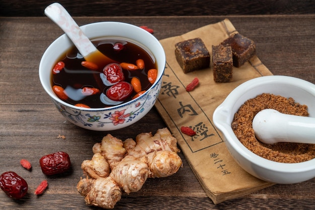 Herbata jujube z brązowego cukru imbiru i klasyczne chińskie książki medyczne na stole