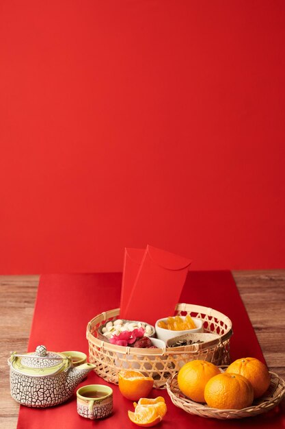 Herbata, smakołyki i owoce podawane na stole ozdobionym czerwonym obrusem z okazji księżycowego Nowego Roku