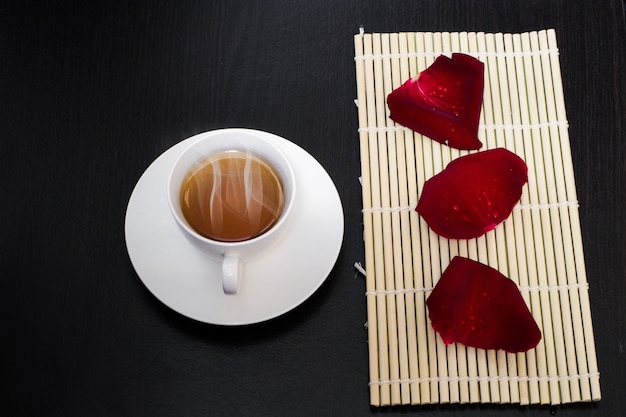 Herbata w białej filiżance z różanym płatkiem na bambusowej podłoga