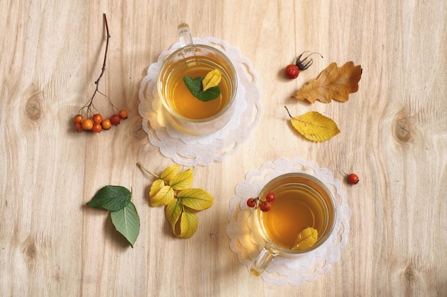 Herbata w szklance na drewnianym stole z liśćmi i jagodami