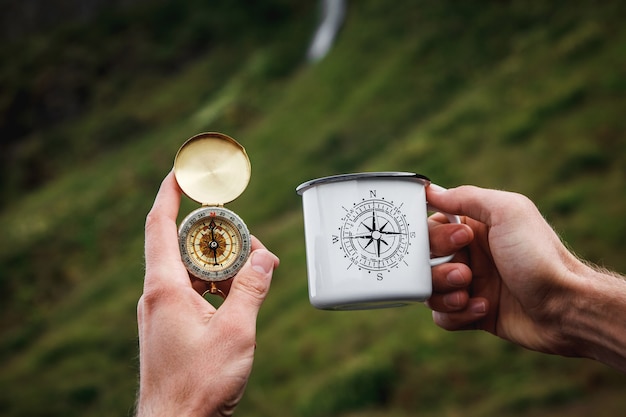 Herbata w turystycznym kubku metalowym i kompasu w dłoni Naturalne tło. Dźwięk w stylu vintage.