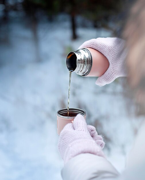 herbata wlewa się z termosu do kubka na zewnątrz