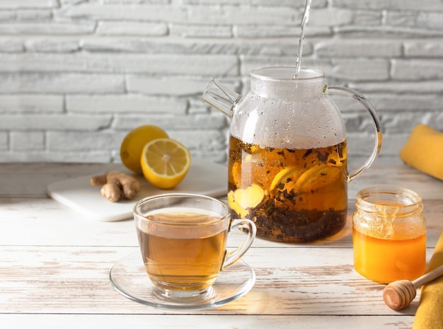 Herbata z cytryną imbirem i miodem na białym drewnianym stole.
