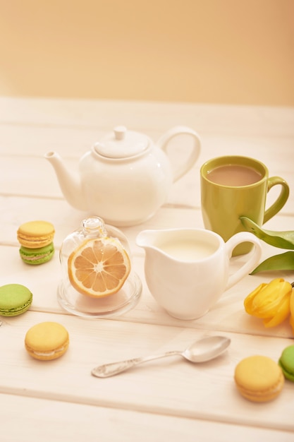 herbata z miętą i cytryną na stole z makaronikami i żółtymi tulipanami