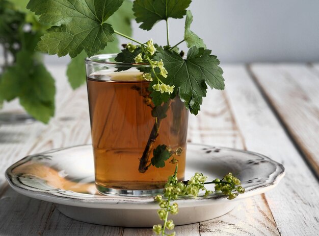 Zdjęcie herbata z roślin w szklanym kubku z kwiatami i użytecznymi ziołami na drewnianym białym stole