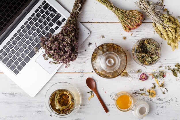 Zdjęcie herbata ziołowa z laptopem i ziołami