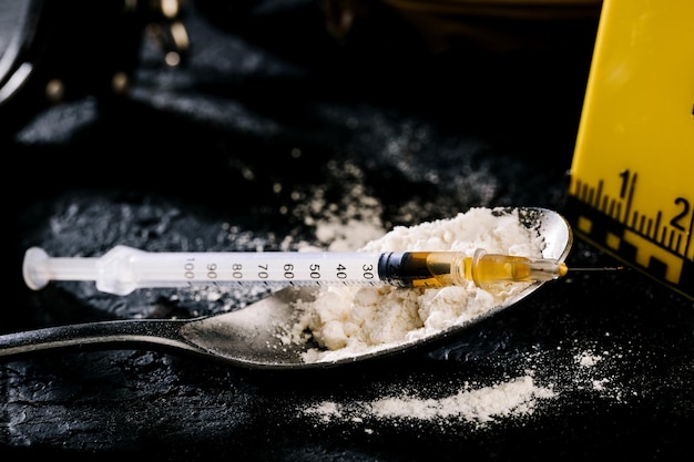 Heroina w strzykawce i heroina w proszku na czarnym tle. pojęcie substancji odurzającej.