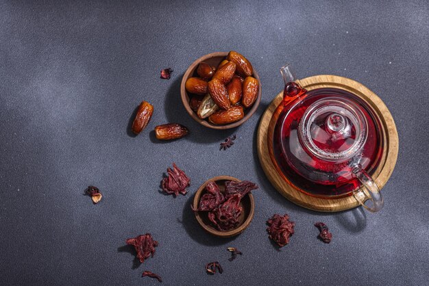 Hibiscus gorąca herbata z datelami Tradycyjny Ramadan Kareem koncepcja przekąska dla Iftar lub Suhoor posiłek na ciemnym kamiennym tle betonowym Arabski słodki przysmak twardy światły ciemny cień widok z góry